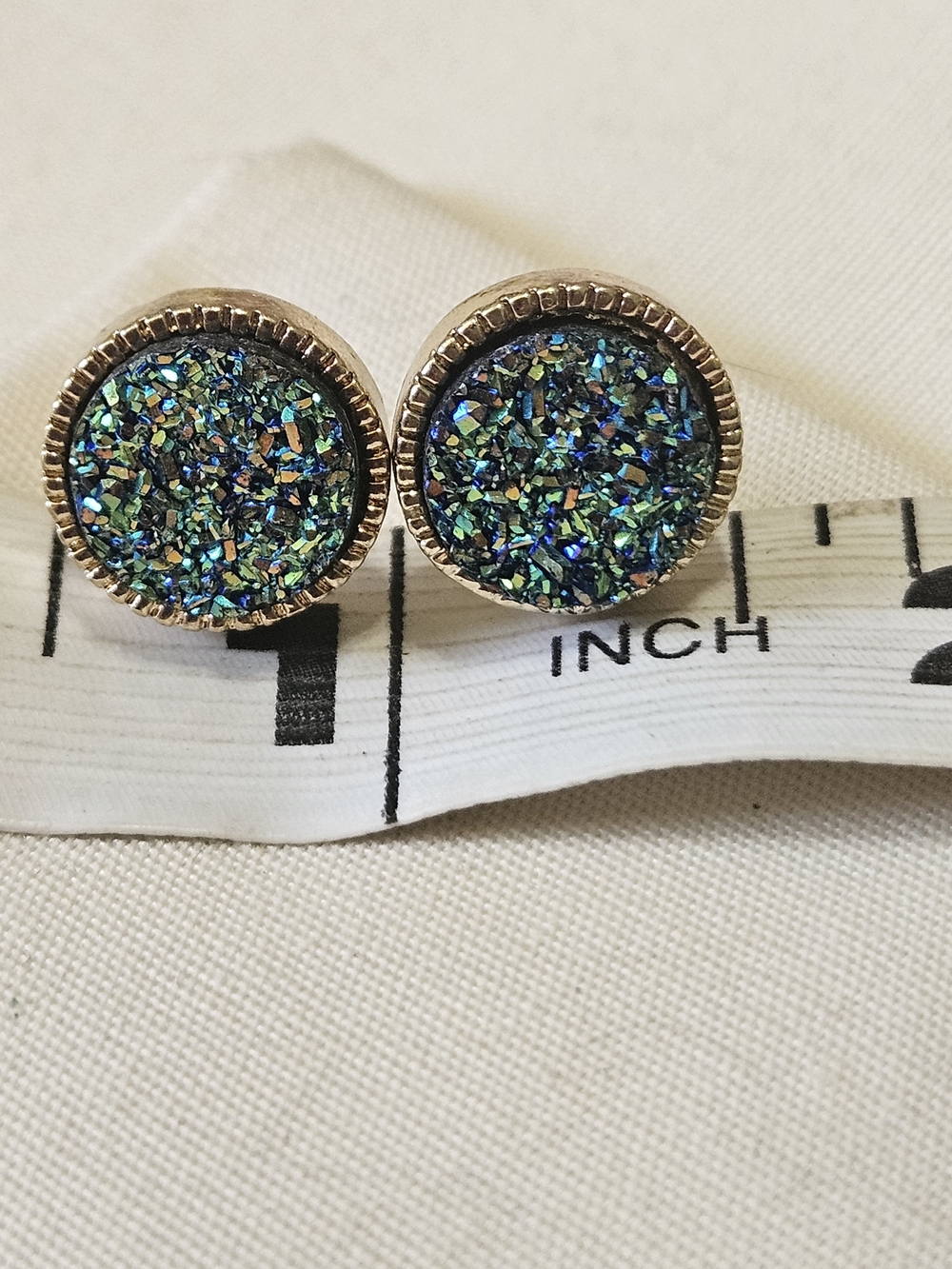 Iridescent blue druzy stud earrings set in a round gold-toned bezel. 